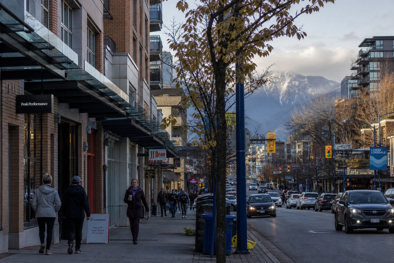 Lower Lonsdale street view — early-twentieth-century wood-frame houses with cedar shingles on the upper storey, Lions Gate Bridge visible in the distance over Burrard Inlet